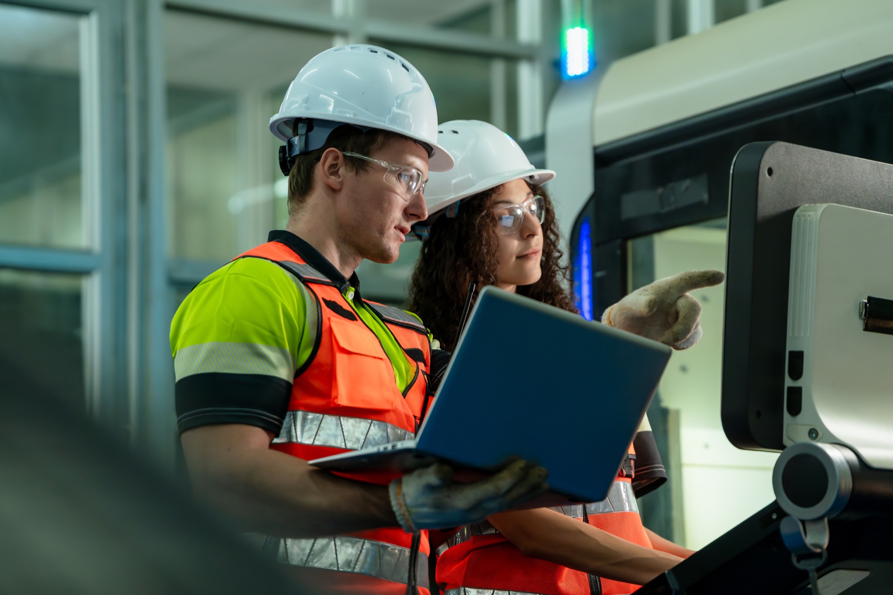 Two engineers reviewing work on a laptop in a factory