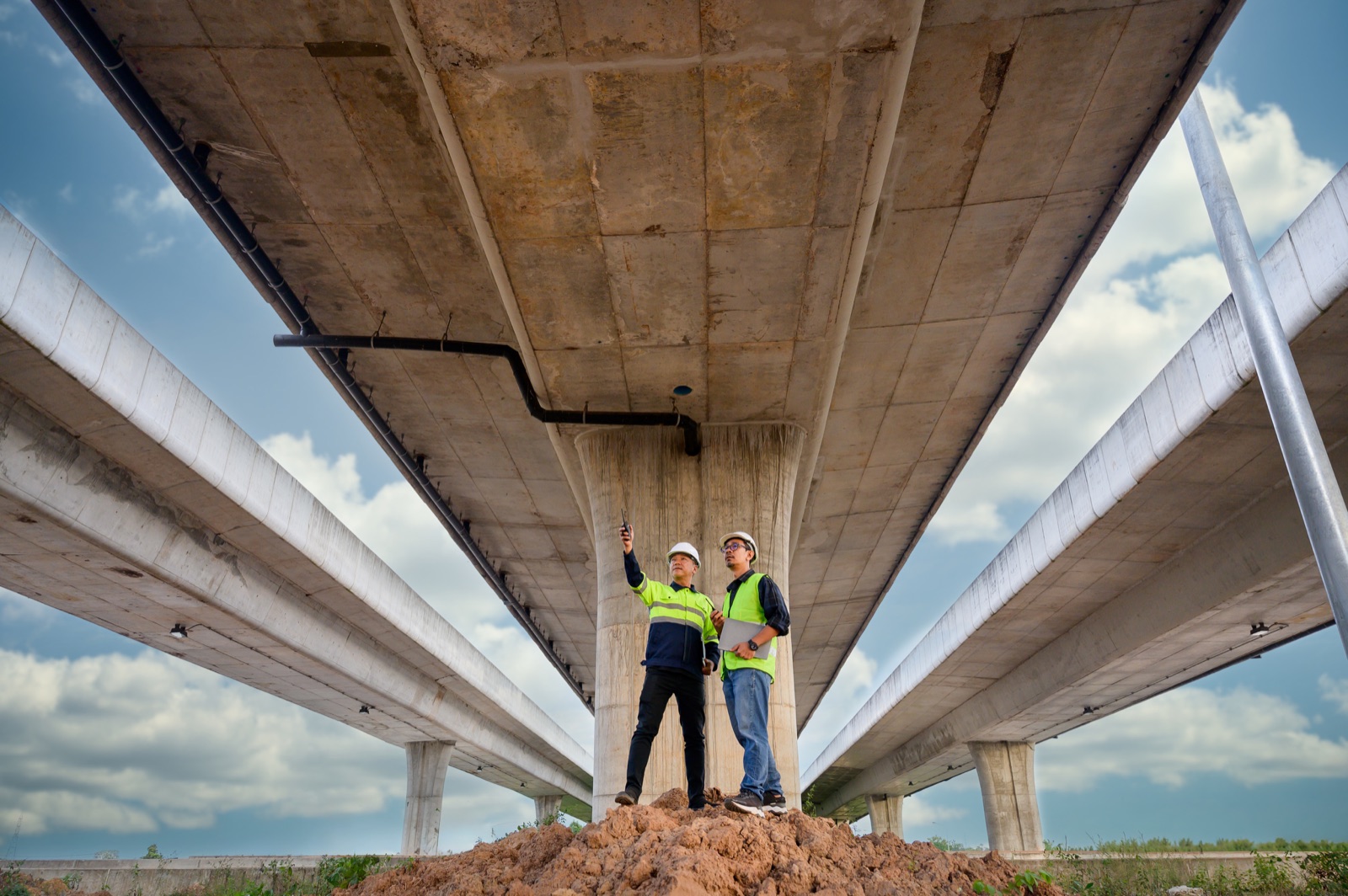 Two engineers standing under a large concrete bridge structure